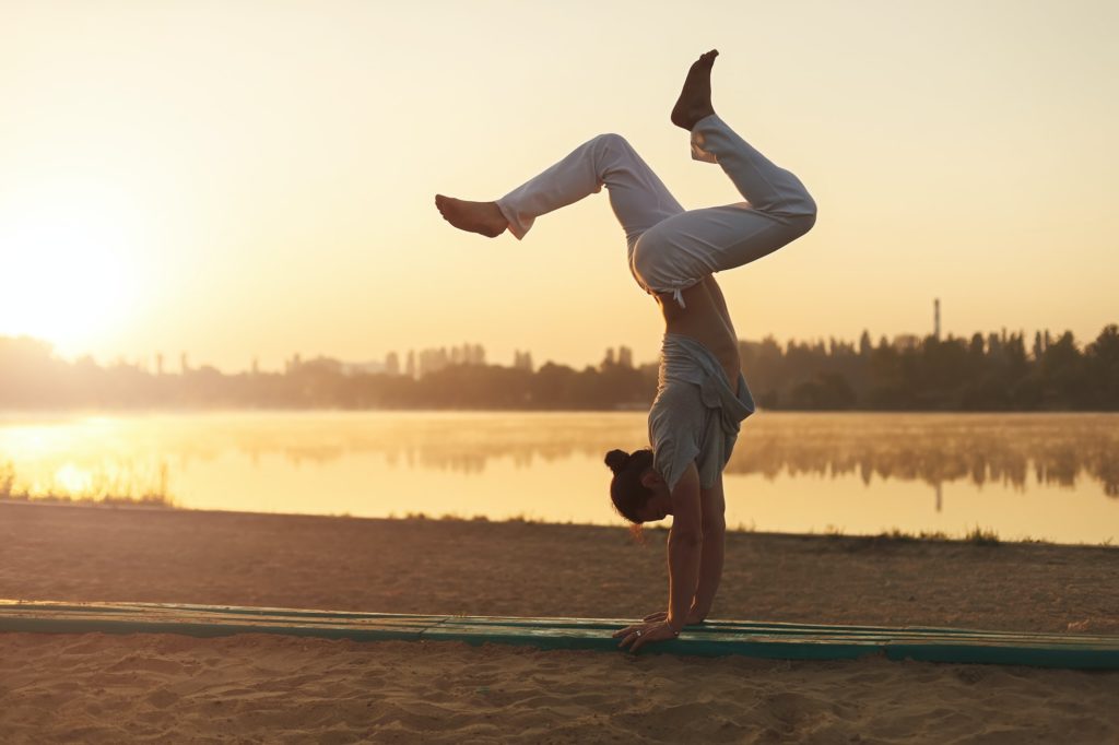 Athletic yoga man workout training on the beach sunrise